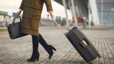 Stylish woman confidently walking through a modern airport terminal with a Beis Travel Tote, highlighting its elegant design and practical features as an organized carry-on bag.