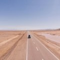 Scenic view of a car driving on an open road towards the horizon, symbolizing freedom, adventure, and the inspirational spirit of a road trip journey, ideal for car travel quotes.