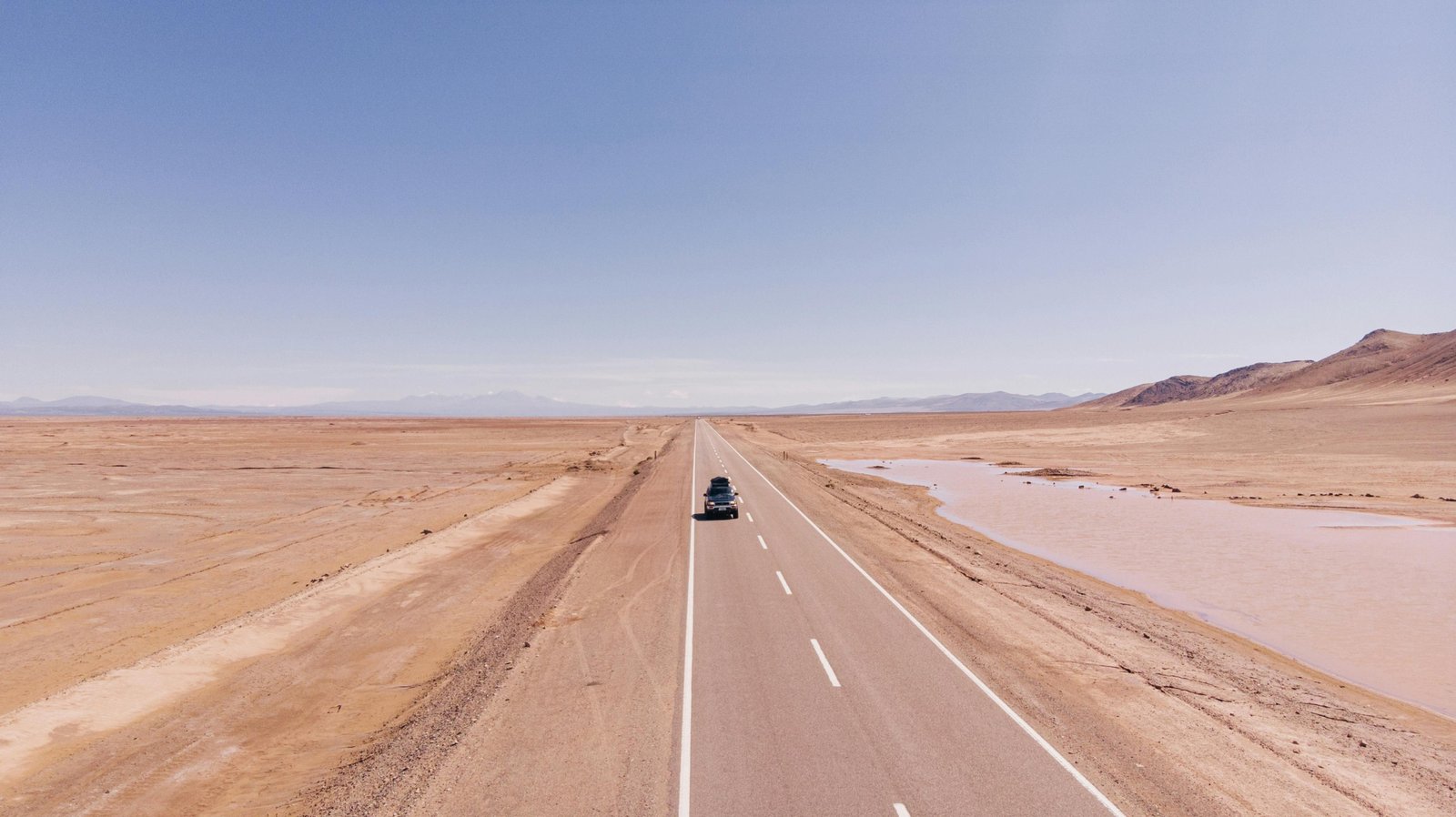 Scenic view of a car driving on an open road towards the horizon, symbolizing freedom, adventure, and the inspirational spirit of a road trip journey, ideal for car travel quotes.