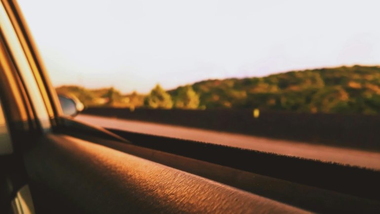 A car driving down a scenic open road through a breathtaking landscape at golden hour, symbolizing freedom, adventure, and the inspiring spirit of car travel and road trip quotes.