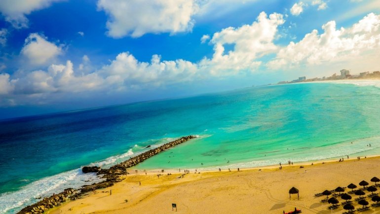 Stunning Cancun beach with crystal-clear turquoise water, white sand, and palm trees under a sunny sky, ideal for planning your perfect vacation to Mexico.