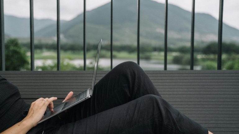An individual confidently creating content on a laptop amidst a breathtaking travel landscape, representing the journey to start a successful travel blog.