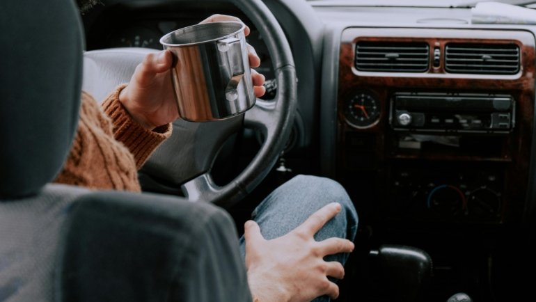 Person enjoying perfectly hot coffee from a sleek smart heated travel mug during their morning commute, highlighting convenience and advanced beverage technology.