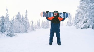 A person confidently wheels a durable ski or snowboard travel bag through an airport terminal, showcasing convenient and protected transport for winter sports gear to the mountains.