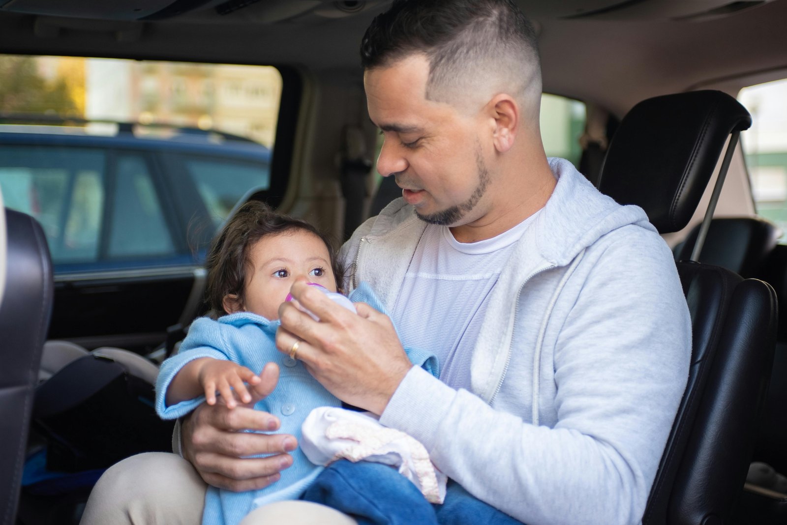 A parent's hand using a portable travel formula dispenser to quickly prepare a baby bottle, illustrating convenient and hygienic feeding for infants on the go during travel.