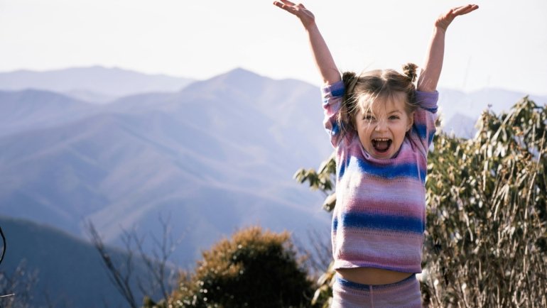 Excited traveler with expressive face in vibrant landscape, illustrating effective YouTube travel thumbnail design for high click-through rates.