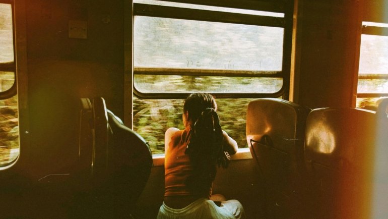 Comfortable train seat with a large window offering a scenic view of the European countryside, representing a relaxing and eco-friendly train journey from Budapest to Prague.