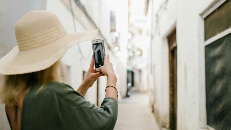 Happy traveler using a smartphone with Spectrum Mobile internationally, managing calls, texts, and data abroad to save on roaming costs.