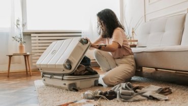 A confident plus-size woman smiling while meticulously arranging her stylish and comfortable travel capsule wardrobe for an enjoyable vacation.