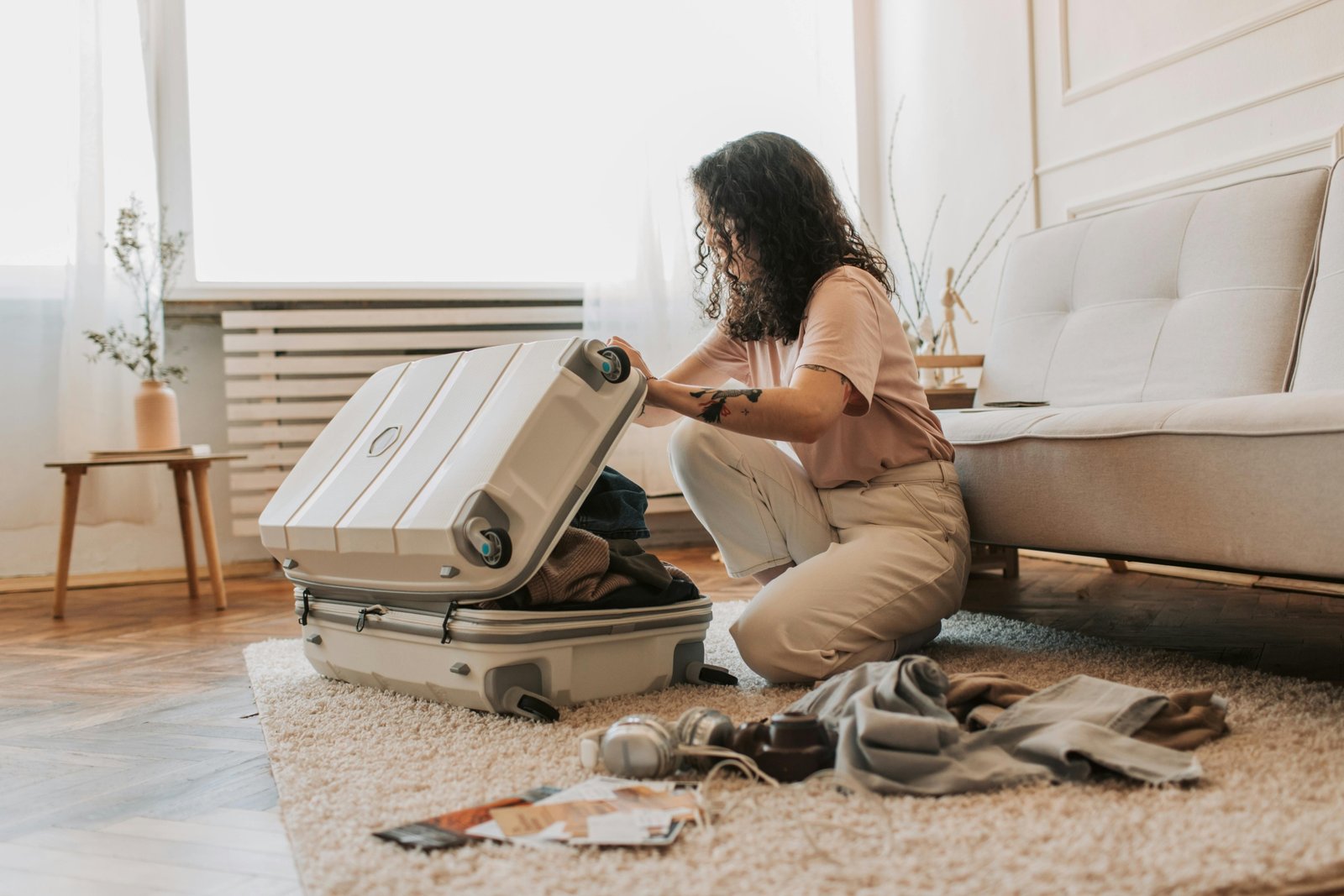 A confident plus-size woman smiling while meticulously arranging her stylish and comfortable travel capsule wardrobe for an enjoyable vacation.