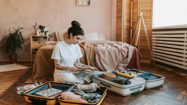 A confident female traveler efficiently packing an open suitcase with stylish and essential items like versatile clothing, solid toiletries, and smart tech, ready for a stress-free adventure.