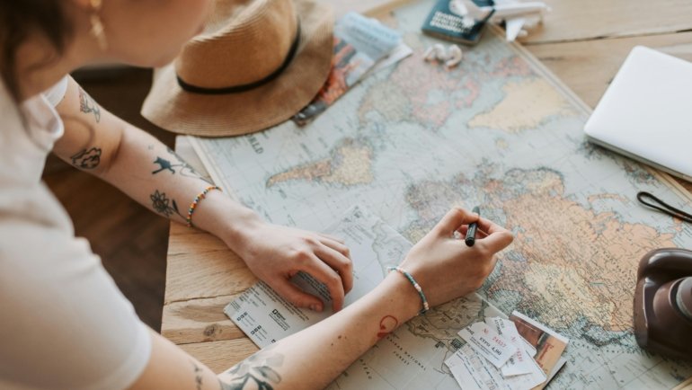 Texas travel agent enthusiastically planning global trips with maps and computer, embodying a successful career in the travel industry.