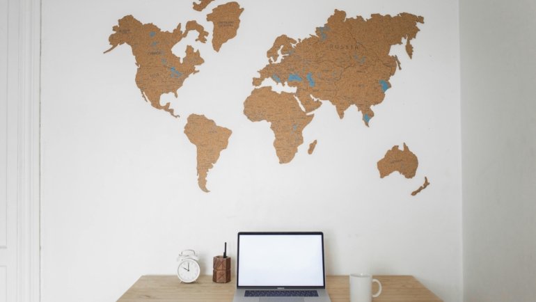 Professional travel coordinator's organized desk with laptop, world map, and travel documents, symbolizing efficient trip planning and logistics management.