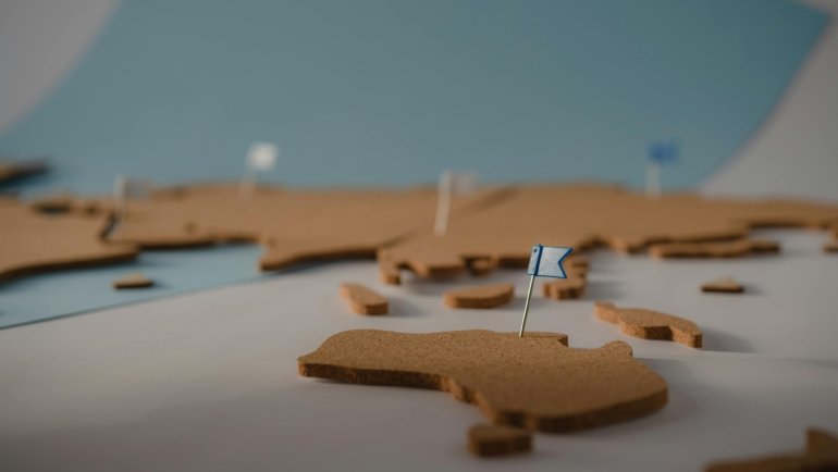 A stylish world travel map with colorful pins on a wall, visualizing a traveler's past adventures and inspiring future plans, ideal for home decor.