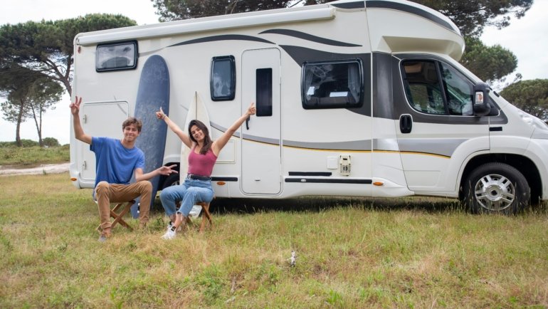 A sleek ultra lite travel trailer with a modern design, easily towable by a small SUV, parked in a picturesque national park campsite, embodying accessible and fuel-efficient lightweight RV adventures.