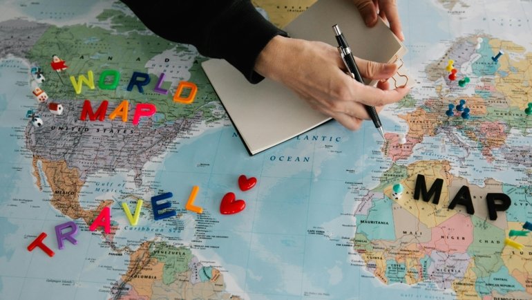 Travel bucket list planning desk with a world map, journal, and various travel inspirations, representing future adventures, cultural experiences, and relaxing trips.