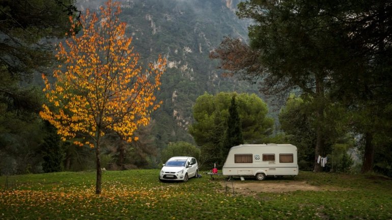 Distinctive R-Pod travel trailer with its unique teardrop shape parked at a picturesque campsite in a natural landscape, ideal for lightweight outdoor adventures.