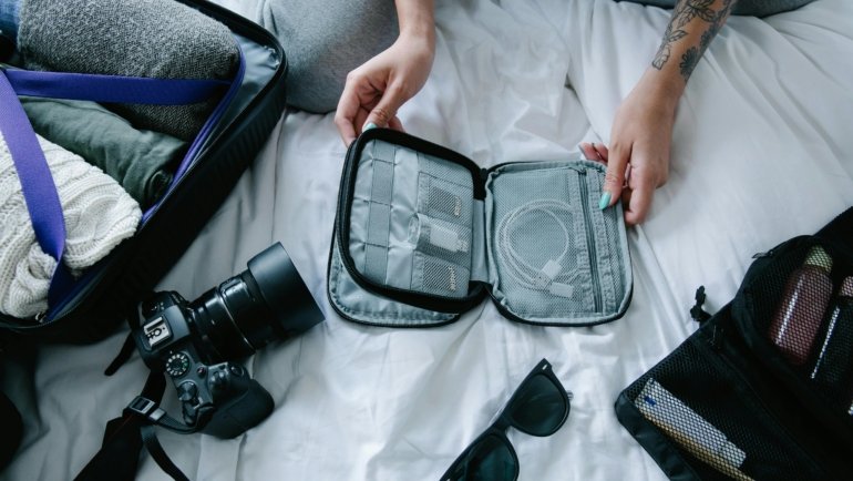 Modern travel box organizer open with neatly arranged electronics (cables, charger, power bank) and toiletries, demonstrating efficient packing for stress-free travel.