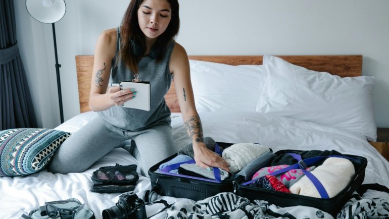 Confident female traveler organizing essential items for a smart packing list for women, featuring versatile clothing and packing cubes for a stress-free trip.