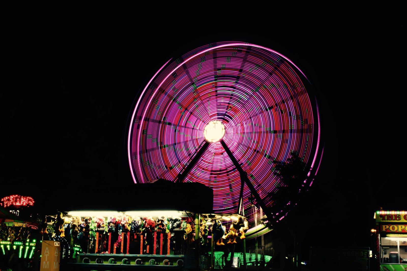 Vibrant traveling carnival at night with illuminated rides such as a Ferris wheel, a bustling crowd, and colorful lights, representing the excitement of mobile amusement parks and community fairs.