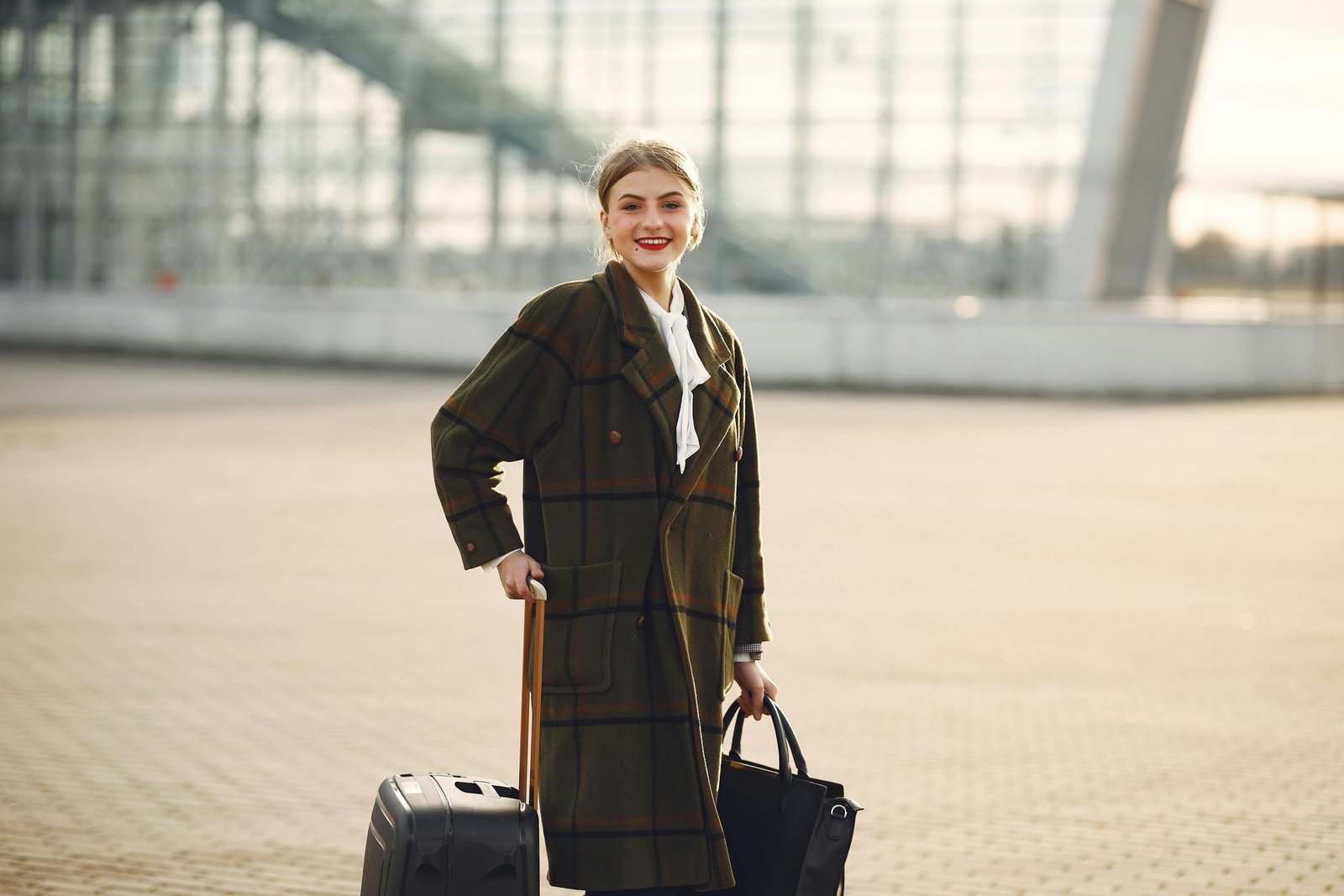 A modern traveler effortlessly navigates a bustling airport terminal, with a stylish personal item bag securely attached to a rolling carry-on suitcase using a smart trolley sleeve, demonstrating hands-free convenience.