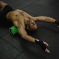 Traveler using a portable foam roller for muscle relief and recovery in a hotel room, emphasizing on-the-go wellness during trips.