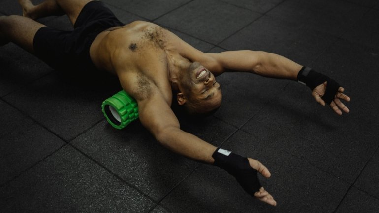 Traveler using a portable foam roller for muscle relief and recovery in a hotel room, emphasizing on-the-go wellness during trips.