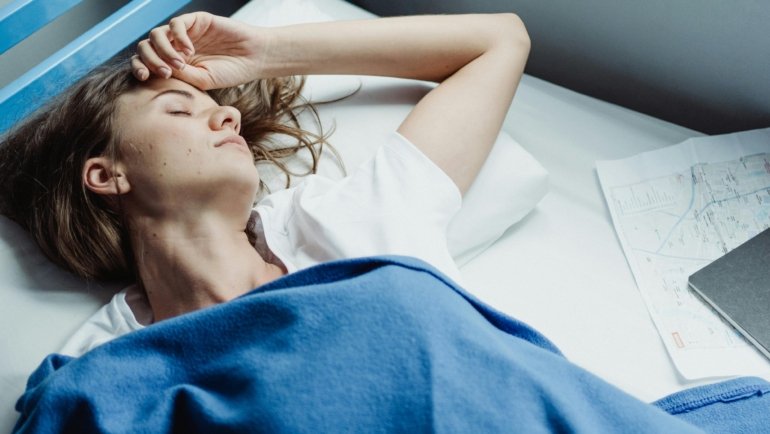 A traveler sleeping soundly and comfortably on an airplane, using the Wander Plus travel pillow for superior ergonomic neck support and a refreshed journey.