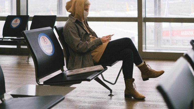 A person wearing a comfortable and stylish smart travel hoodie with multiple features, relaxing in an airport setting, symbolizing essential gear for a better travel experience.