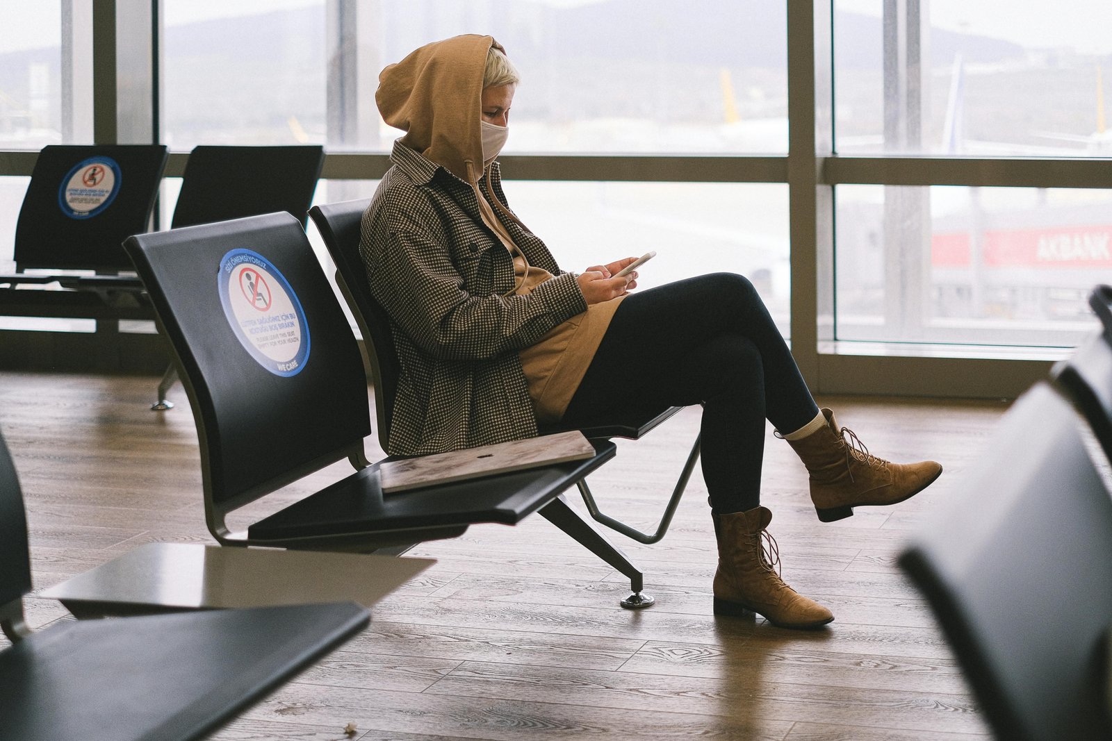 A person wearing a comfortable and stylish smart travel hoodie with multiple features, relaxing in an airport setting, symbolizing essential gear for a better travel experience.