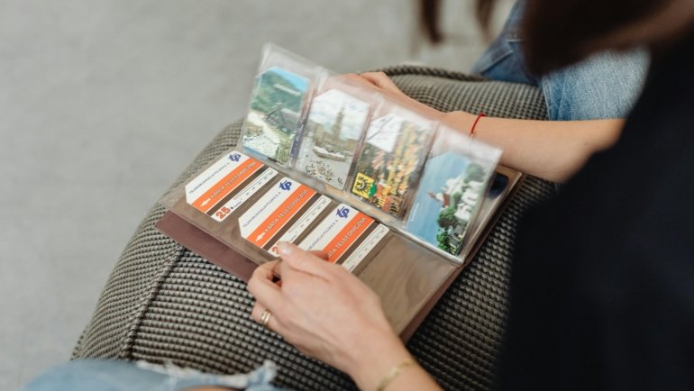 Close-up of hands turning pages of a physical travel photo album, filled with curated memories and photos from past adventures, highlighting the tangible joy of storytelling.