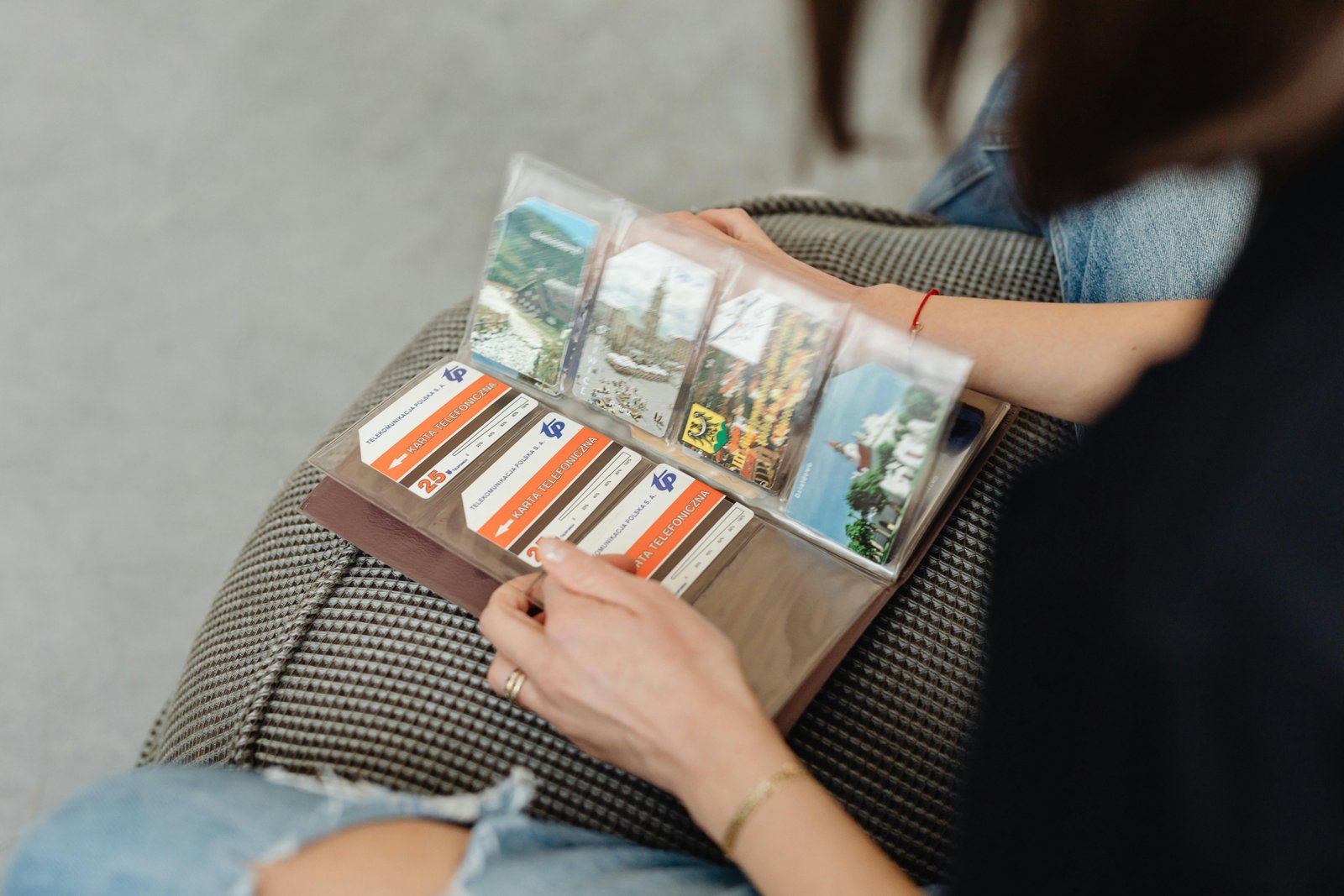 Close-up of hands turning pages of a physical travel photo album, filled with curated memories and photos from past adventures, highlighting the tangible joy of storytelling.