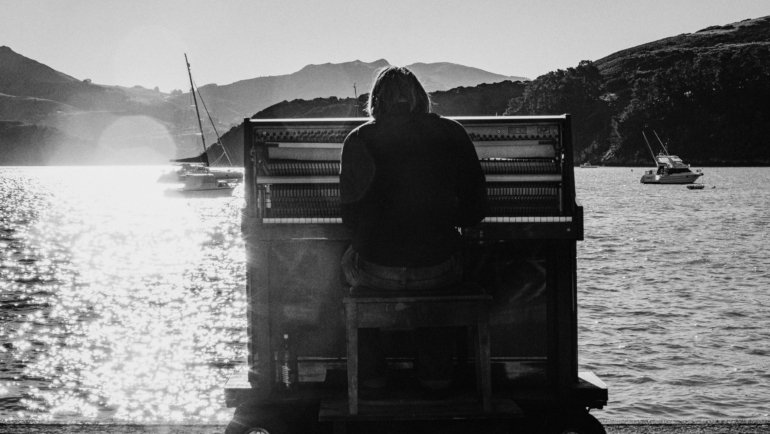 A musician playing a lightweight portable travel piano in a scenic outdoor setting, demonstrating how easily musicians can practice and compose music on the go during their adventures.