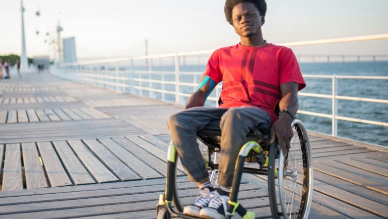 A person happily using a lightweight folding electric wheelchair to explore an outdoor travel destination, symbolizing enhanced mobility, independence, and the joy of adventure.