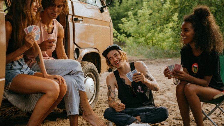 Friends laughing and playing a compact travel game together, highlighting fun and connection on a trip or vacation.