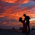 Romantic couple watching a sunset on a beach during a dreamy vacation