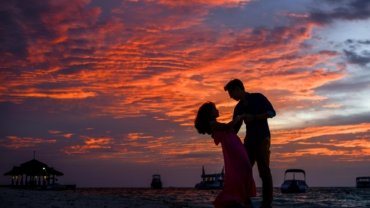 Romantic couple watching a sunset on a beach during a dreamy vacation