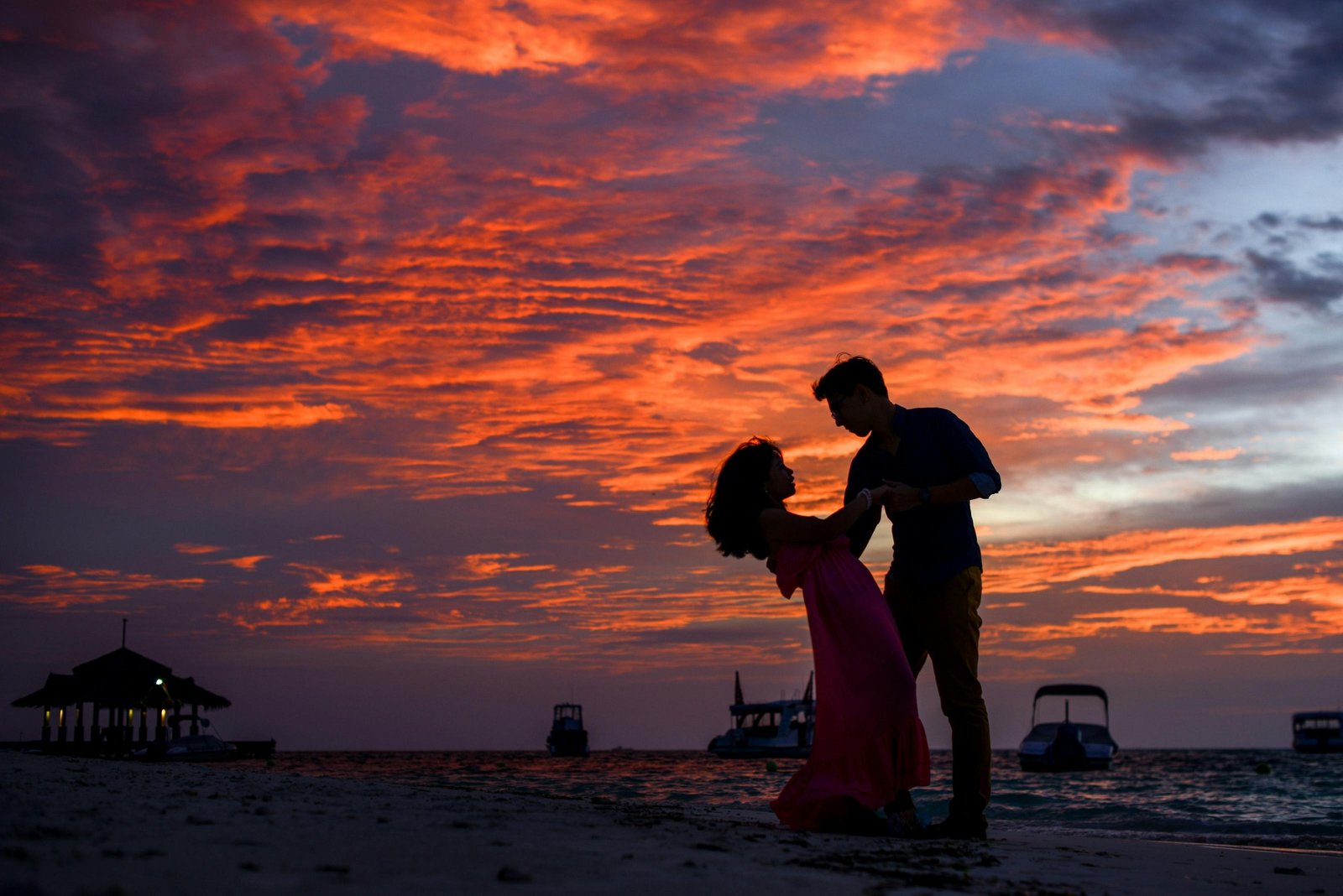 Romantic couple watching a sunset on a beach during a dreamy vacation