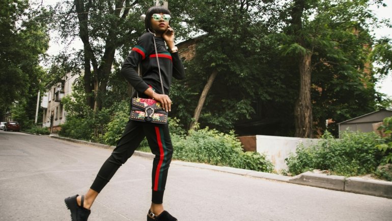 Stylish woman carrying a secure crossbody travel purse in a busy European city street