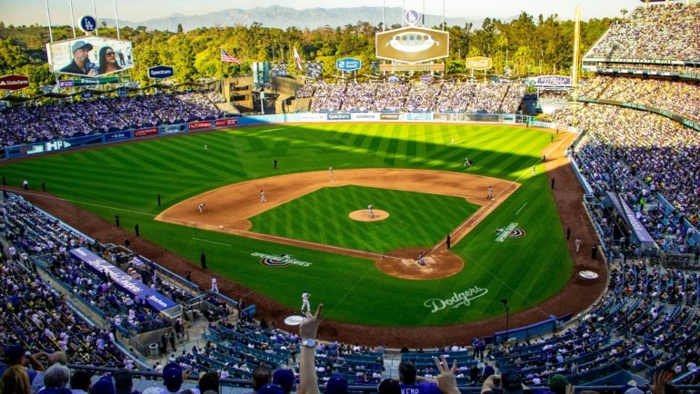 Excited baseball fans cheering in a packed stadium during a sunny day baseball travel trip
