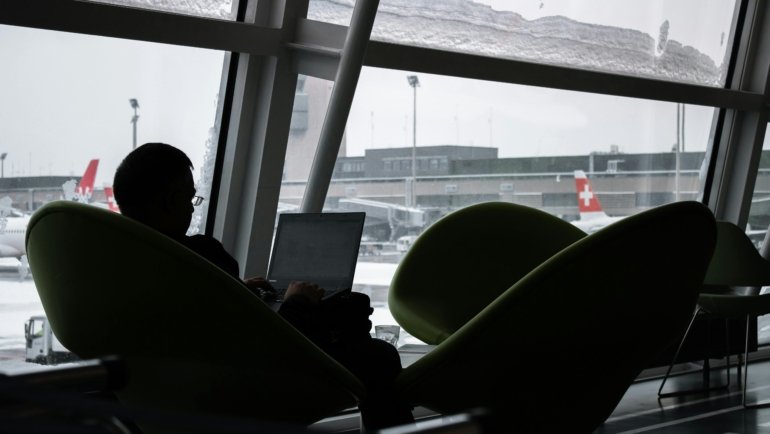 Business traveler using laptop to manage United Airlines travel credits and American Express Platinum benefits in airport lounge