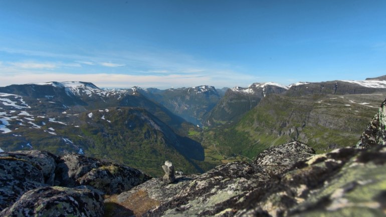 Scenic Norwegian fjords in summer with green hills, calm water, and bright daylight