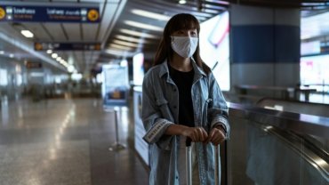 Woman holding a stylish and secure travel wallet at the airport, illustrating organized and stress-free travel for women
