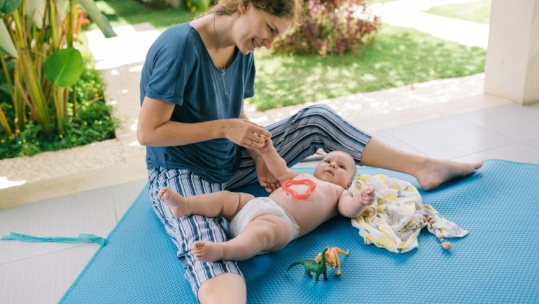 Parent using a portable waterproof travel changing mat to change baby’s diaper outdoors
