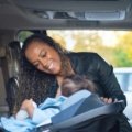 Family traveling safely with a child securely seated in a traveling car seat during a family road trip