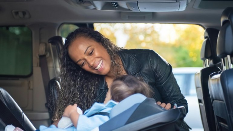 Family traveling safely with a child securely seated in a traveling car seat during a family road trip