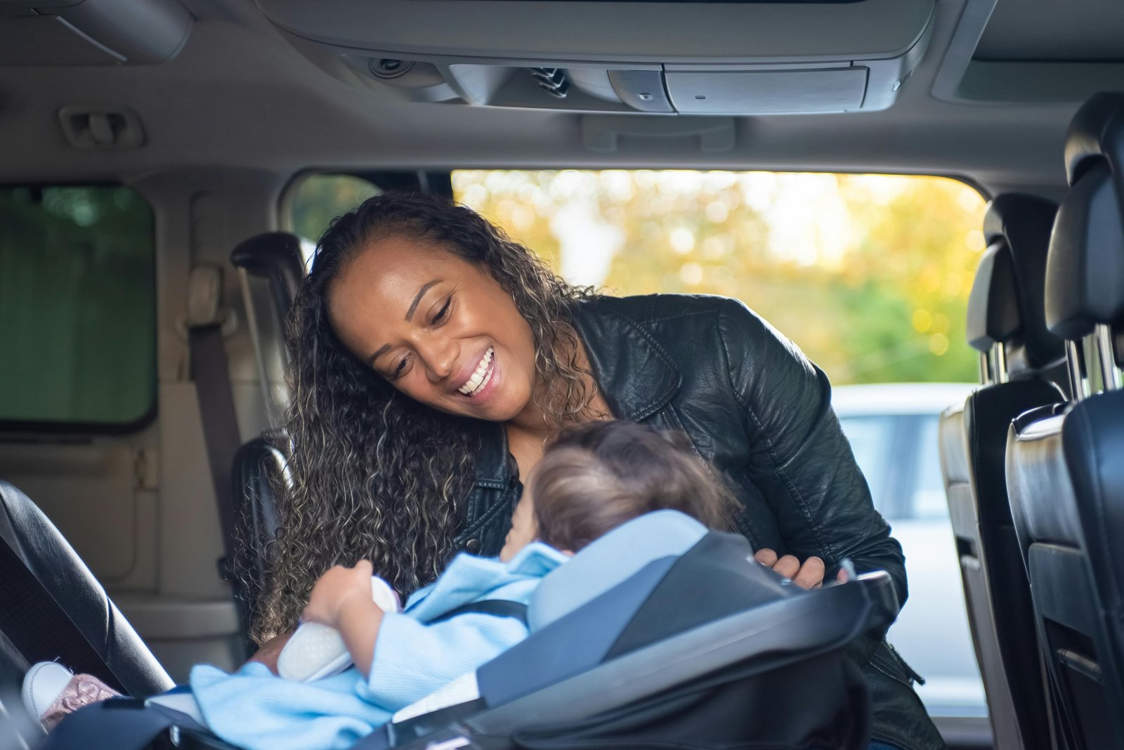 Family traveling safely with a child securely seated in a traveling car seat during a family road trip