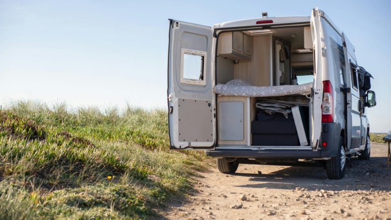 Hybrid travel trailer with fold-out tent beds parked at a scenic campsite, highlighting comfort and versatility in outdoor camping