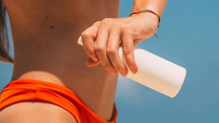 Traveler applying portable travel sun spray outdoors for skin protection against UV rays