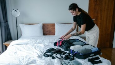 Woman traveler organizing suitcase with packing cubes and travel accessories for a trip